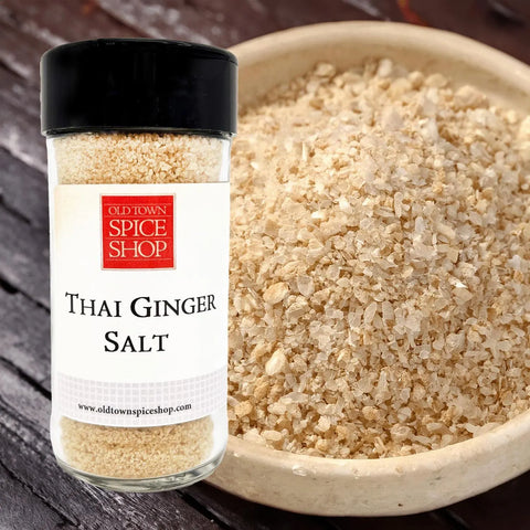 Jar of Old Town Spice Shop Thai Ginger Salt next to a bowl of the salt on a wooden surface.