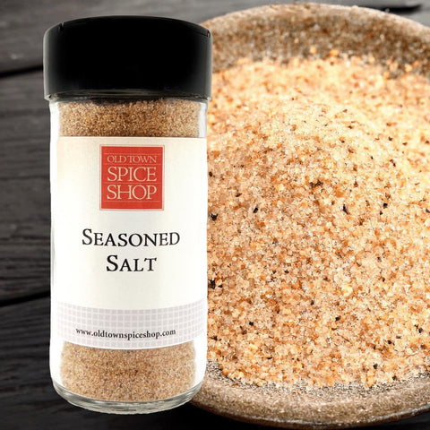 Bottle of Old Town Spice Shop seasoned salt next to a bowl of the product on a wooden surface.