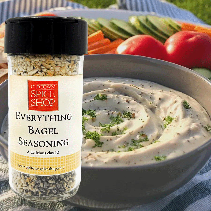 Bottle of Old Town Spice Shop Everything Bagel Seasoning with a bowl of dip and vegetables in the background.