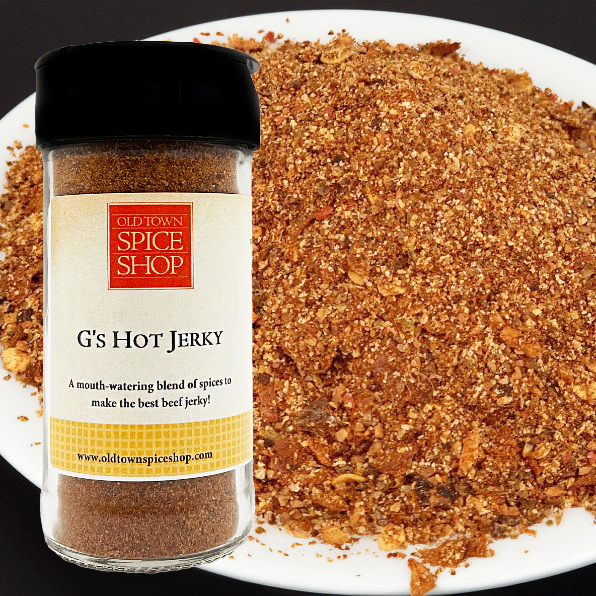 Spice jar labeled 'G's Hot Jerky' from Old Town Spice Shop with a background of ground spice mixture.
