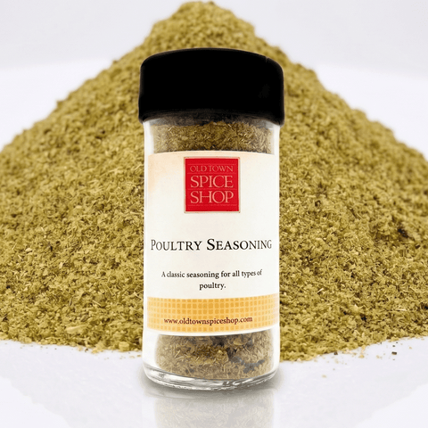 A clear plastic spice jar of Old Town Spice Shop Poultry Seasoning with a black lid and cream label, set in front of a large mound of the greenish-yellow seasoning on a white background.