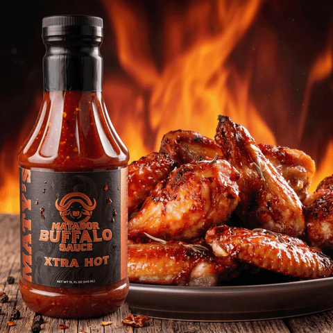 Bottle of Maty's Natacor Buffalo Sauce Xtra Hot with grilled chicken wings on a wooden surface.