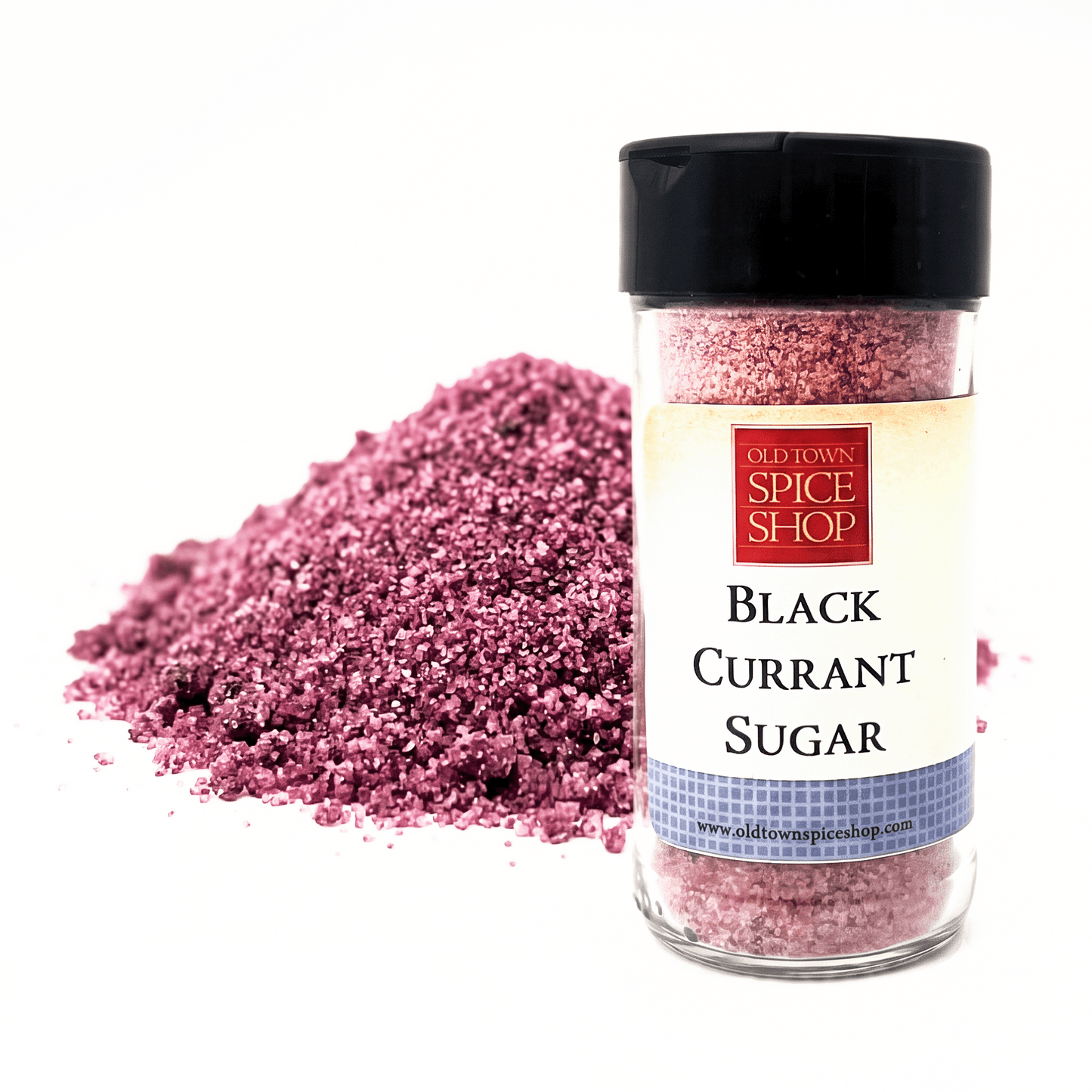 A clear plastic spice jar labeled 'Old Town Spice Shop Black Currant Sugar' with a black lid, shown next to a pile of pinkish-purple coarse sugar crystals on a white background.