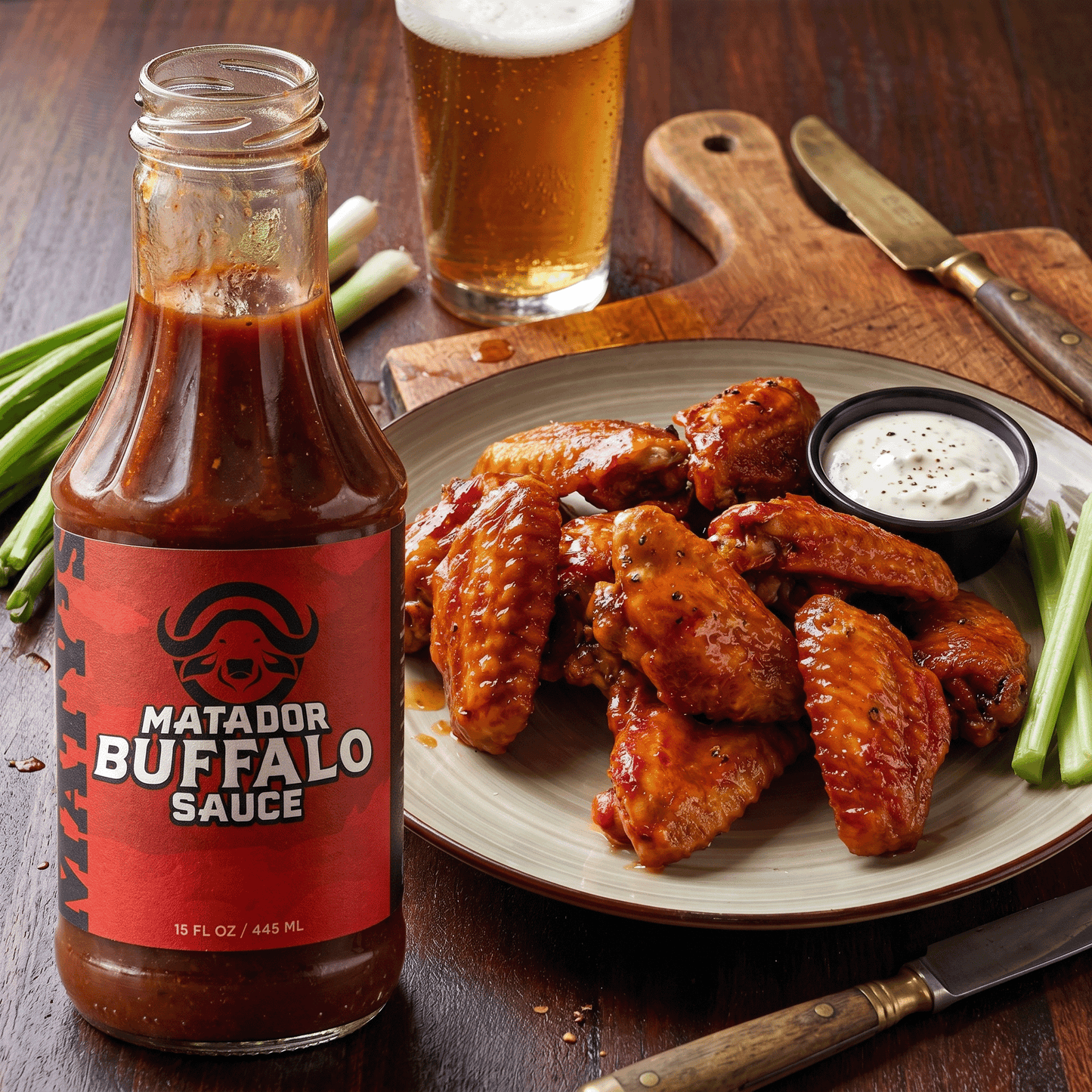 Matador Buffalo Sauce bottle with wings and beer on a wooden table