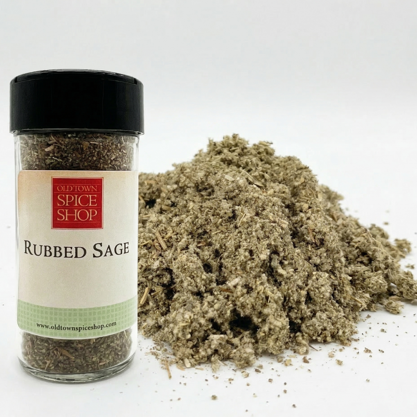 Jar of rubbed sage from Old Town Spice Shop with a pile of sage on a white background