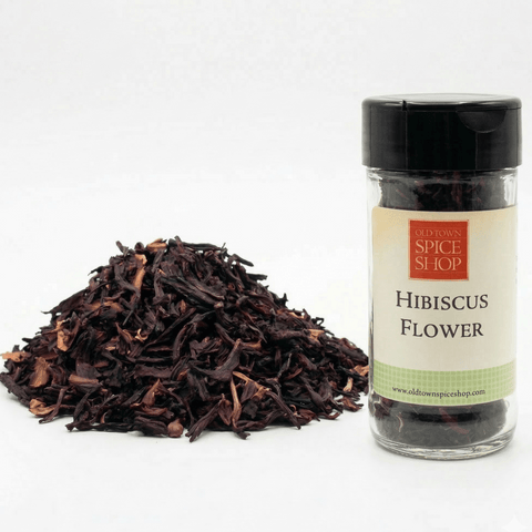 Jar of hibiscus flower from Old Town Spice Shop with dried hibiscus leaves on a white background