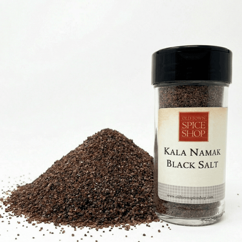 Jar of Kala Namak black salt from Old Town Spice Shop with spilled salt on a white background