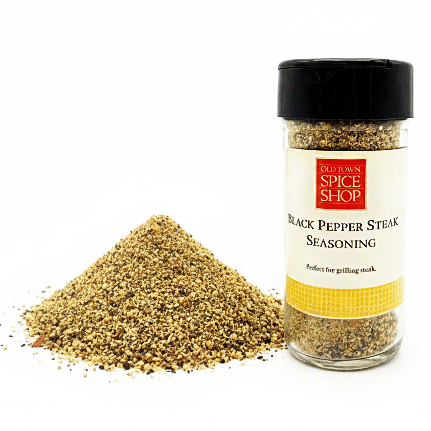 Spice jar labeled 'Black Pepper Steak Seasoning' from Old Town Spice Shop with spilled seasoning on a white background.