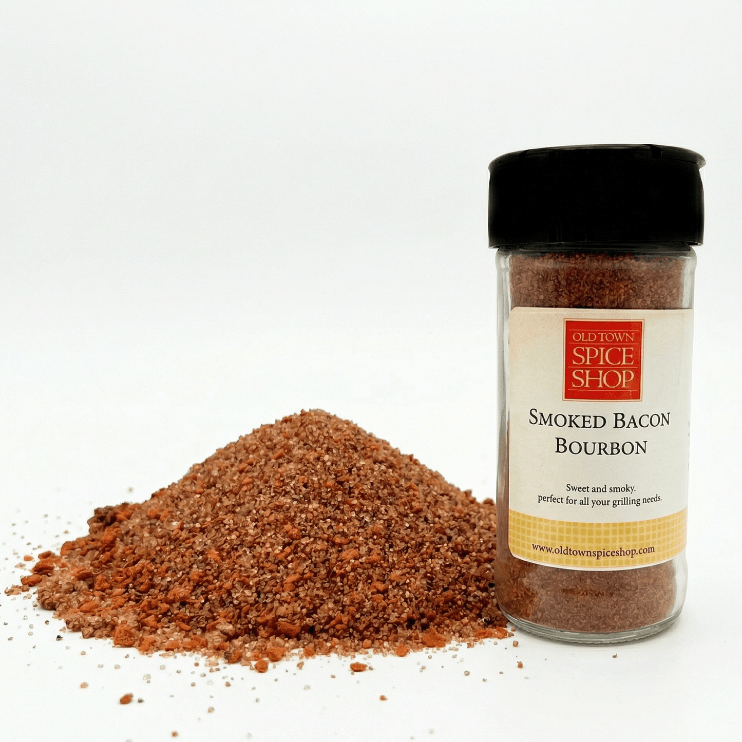 Spice jar labeled 'Smoked Bacon Bourbon' from Old Town Spice Shop with spilled spice on a white background