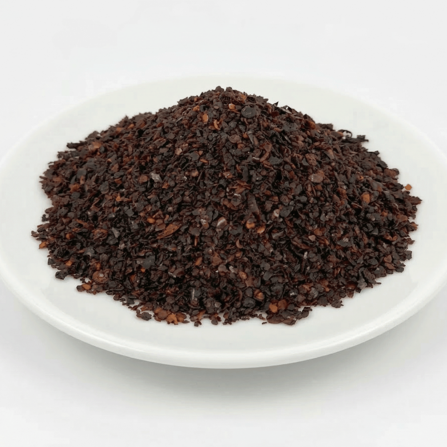 Pile of dark brown ground coffee on a white plate