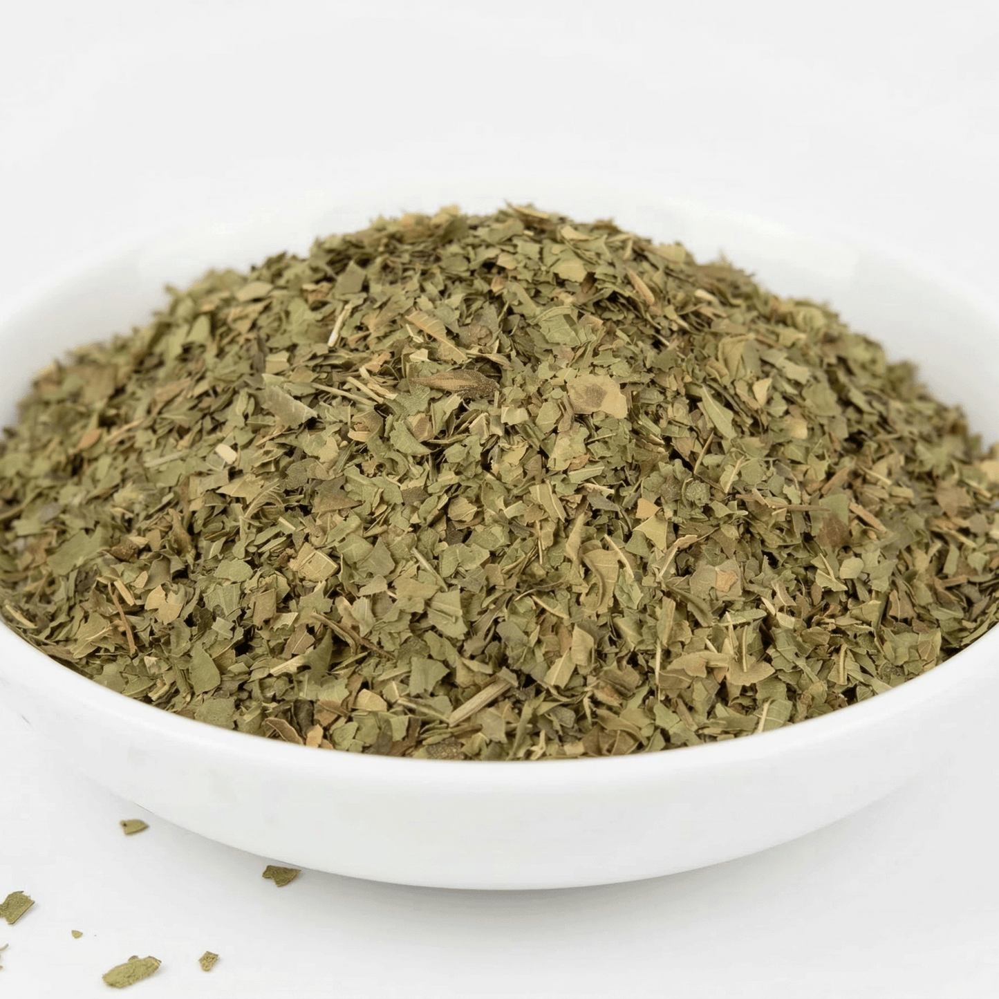 Dry herbs in a white bowl on a white background