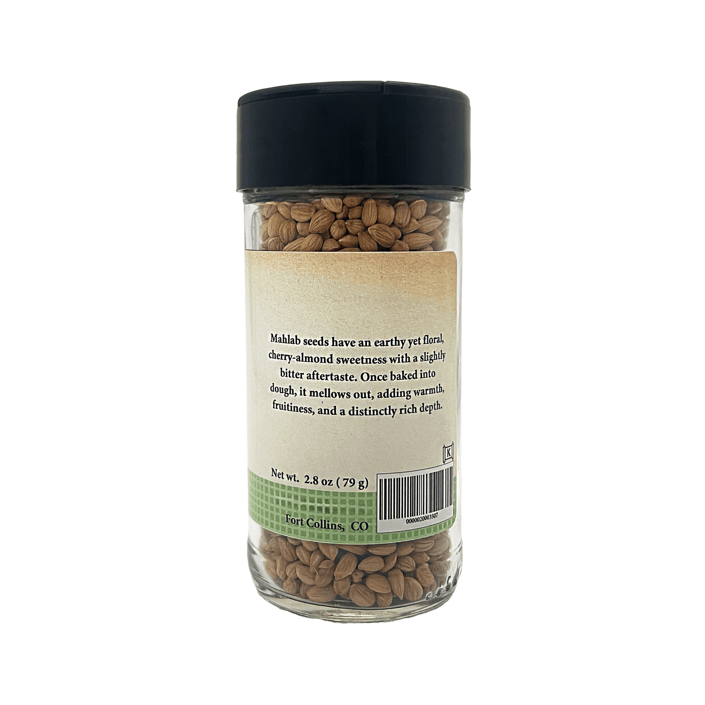 Glass jar of mahlab seeds with a black lid on a white background
