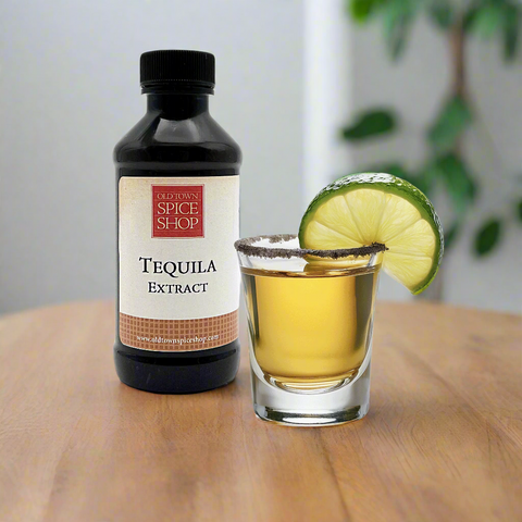Tequila extract bottle with a glass of tequila and lime wedge on a white background