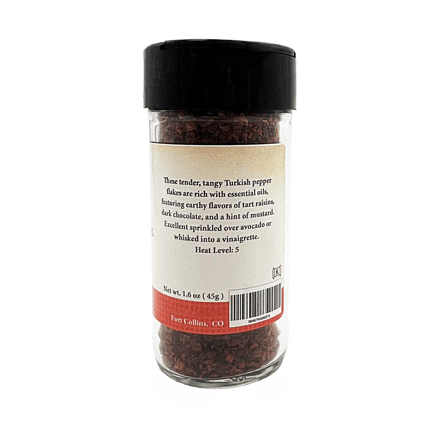 Glass jar of Turkish pepper flakes with a black lid on a white background