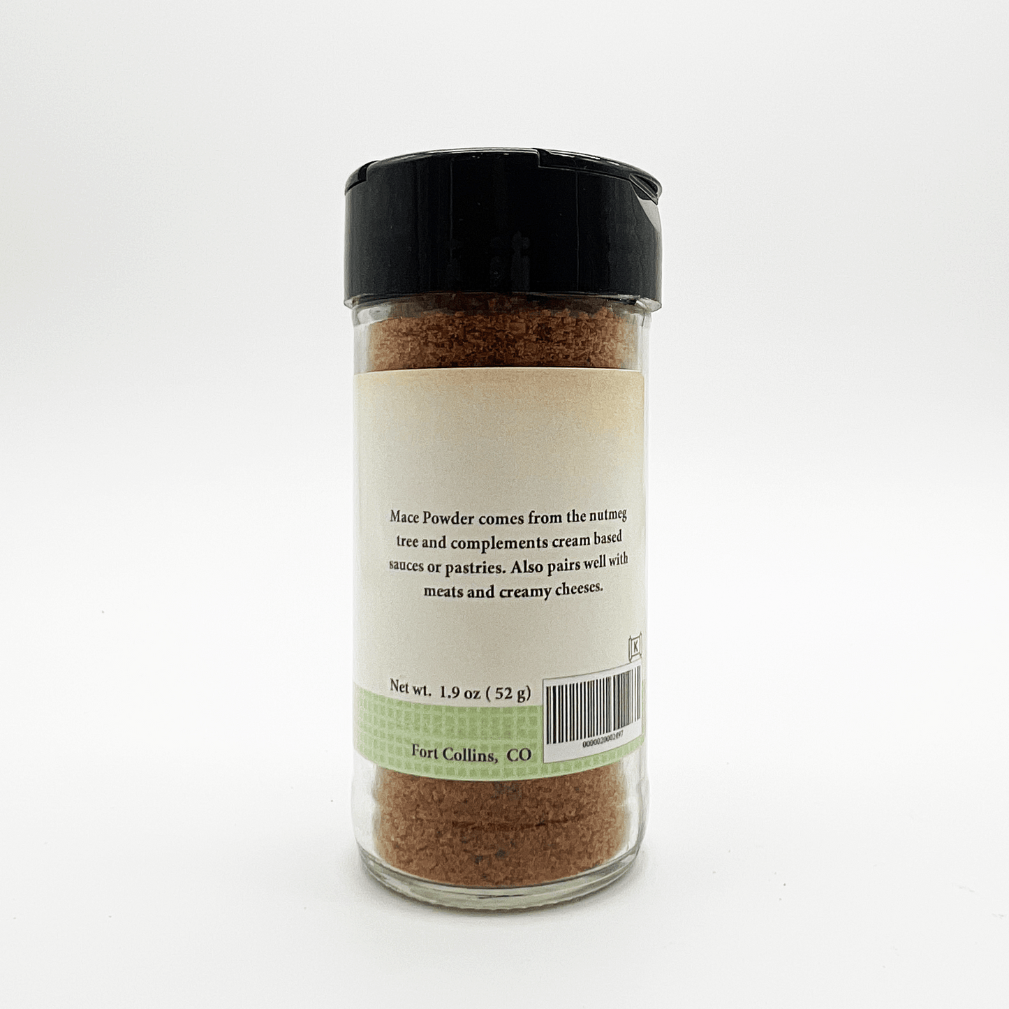 A clear plastic spice jar filled with brown powder, featuring a black flip-top lid and a cream label with product details and a light green band near the bottom.